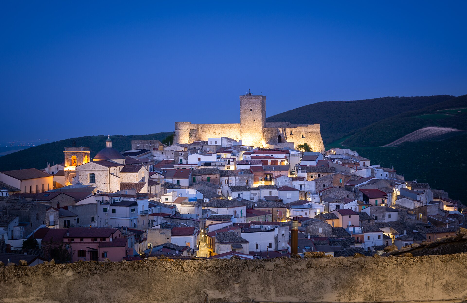 Vista serale di Deliceto: case del borgo e Castello normanno-svevo illuminato